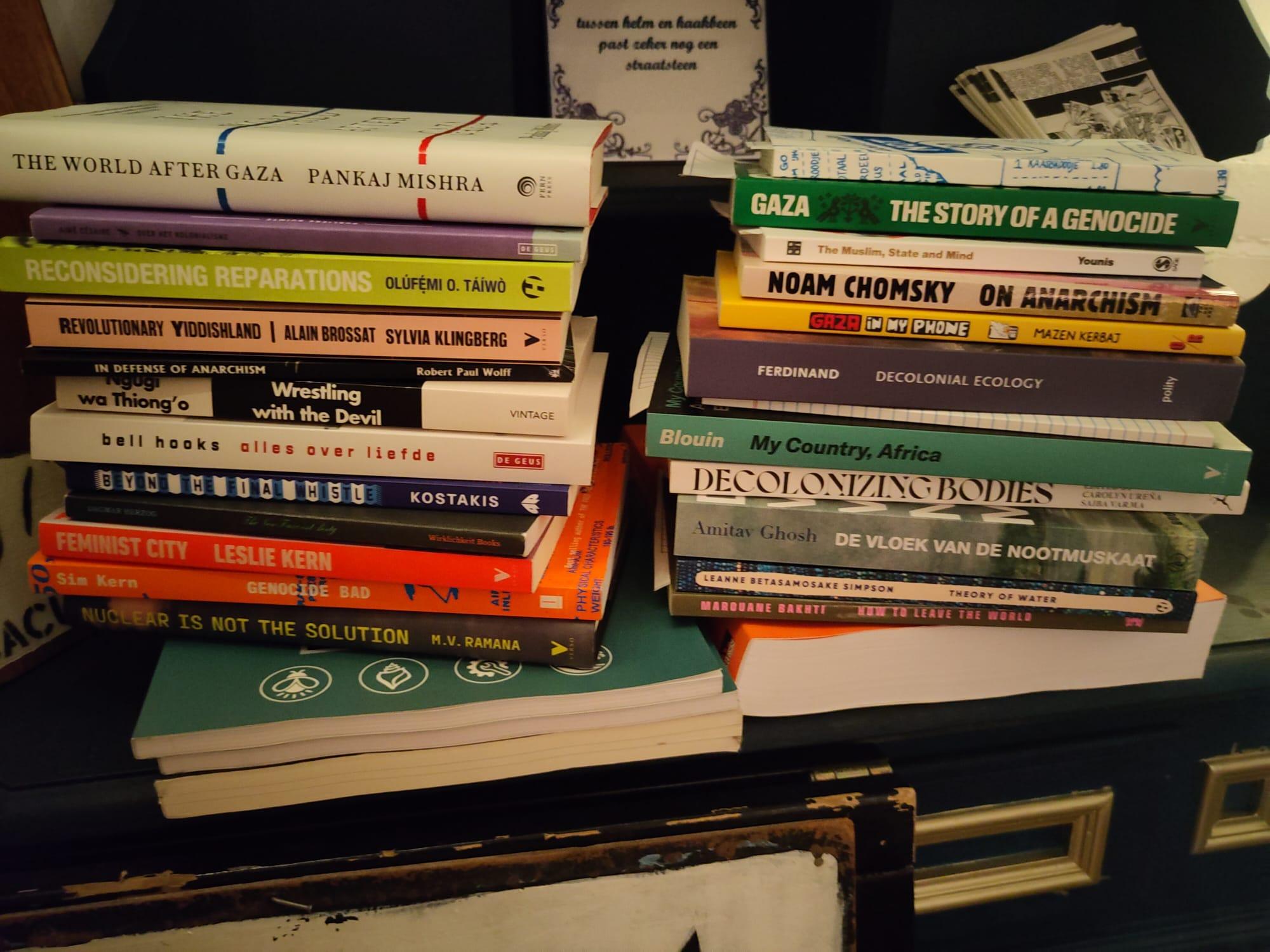 2 piles of books, on the left there are 12 books, and on the right there are 11 books. They are placed on top of a dark blue chest of drawers.